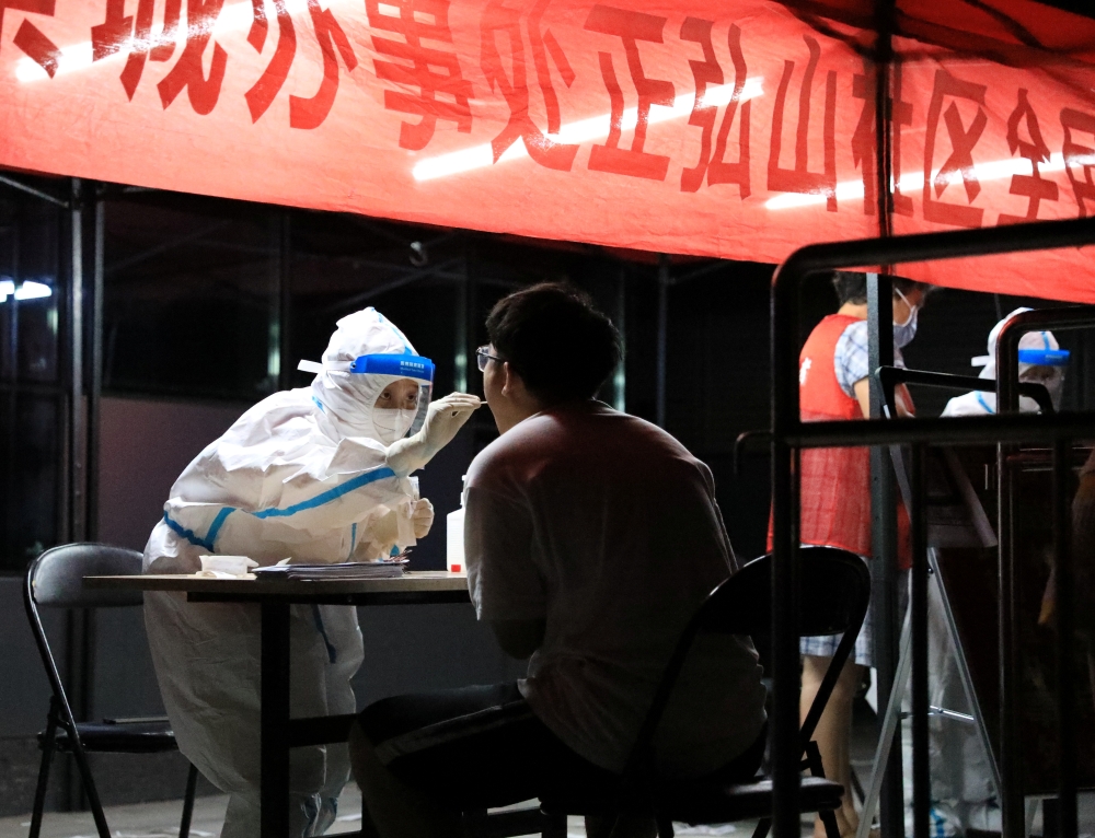 A medical worker in protective suit collects a swab from a resident for nucleic acid testing following new cases of the coronavirus disease (COVID-19) in Zhengzhou, Henan province, China early August 2, 2021. cnsphoto via Reuters 
