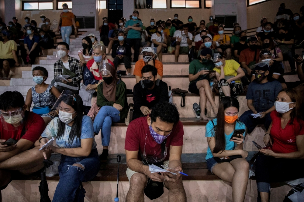 Filipinos use their smartphones while queueing for free vaccination against the coronavirus disease (COVID-19) at San Andres Sports Complex in Manila, Philippines, July 21, 2021. REUTERS/Eloisa Lopez/File Photo/File Photo