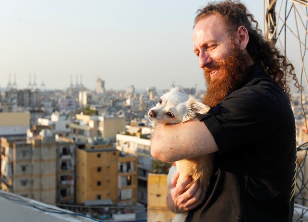 Shady Rizk, a survivor wounded during last year's Beirut port blast, holds his dog on the rooftop of his house, in Sin el-Fil, Lebanon July 30, 2021. REUTERS/Aziz Taher
