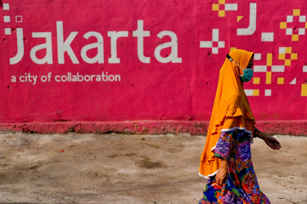 A woman wearing a protective mask walks near a traditional market amid the coronavirus disease (COVID-19) pandemic in Jakarta, Indonesia, July 30, 2021. REUTERS/Willy Kurniawan/File Photo