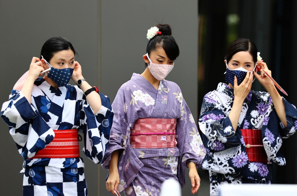 Women in traditional costumes, wearing protective face masks, walk outside the National Stadium, the main venue of the Tokyo 2020 Olympic Games, amid the coronavirus disease (COVID-19) outbreak, in Tokyo, Japan, August 3, 2021. Reuters/Kim Kyung-Hoon