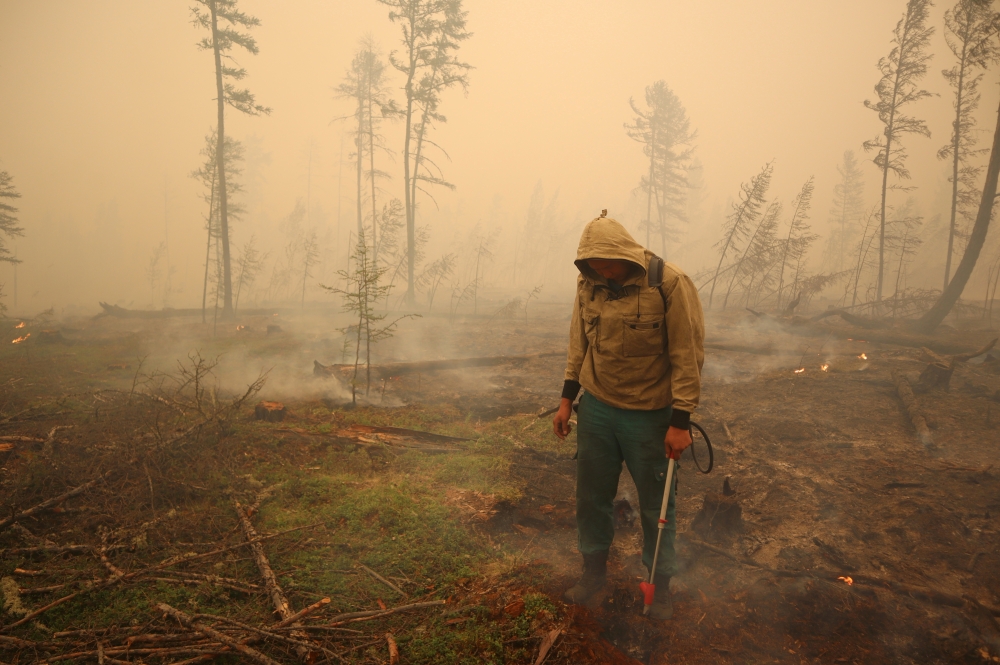 A specialist of the local forest protection service works to extinguish a forest fire near the village of Magaras in the region of Yakutia, Russia July 17, 2021. Picture taken July 17, 2021. REUTERS/Roman Kutukov/File Photo/File Photo