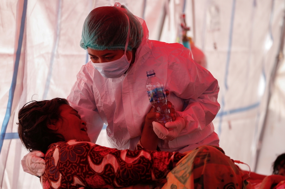 A healthcare worker in personal protective equipment (PPE) treats a patient inside a temporary tent erected outside the emergency ward for accommodating the lack of beds at a government-run hospital amid the surge of coronavirus disease (COVID-19) in Beka