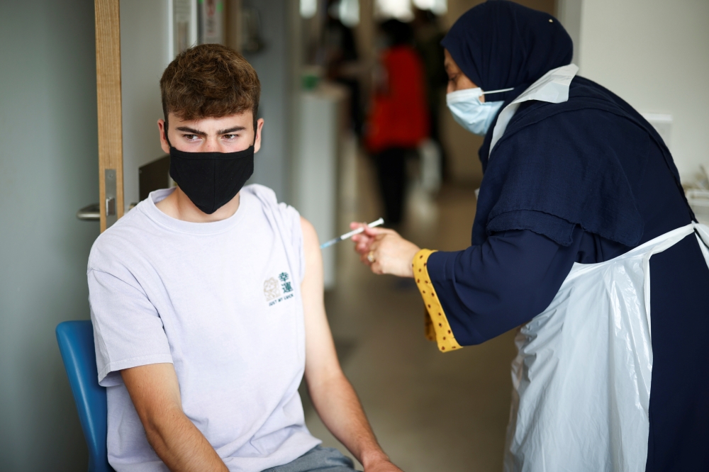 A person receives a dose of the Pfizer BioNTech vaccine at the Central Middlesex Hospital in London, Britain, August 1, 2021. REUTERS/Henry Nicholls/File Photo