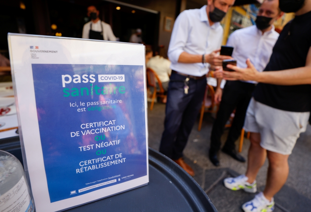 A man shows his COVID-19 health pass at a restaurant as France brings on tougher restrictions where a proof of immunity will now be required to access most public spaces and to travel by inter-city train, in Nice, France, August 9, 2021. REUTERS/Eric Gail
