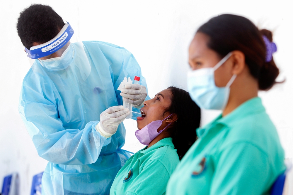 A medical worker wearing personal protective equipment (PPE) takes a swab sample from a person to be tested for coronavirus disease (COVID-19) in Dili, East Timor, August 10, 2021. REUTERS/Lirio da Fonseca