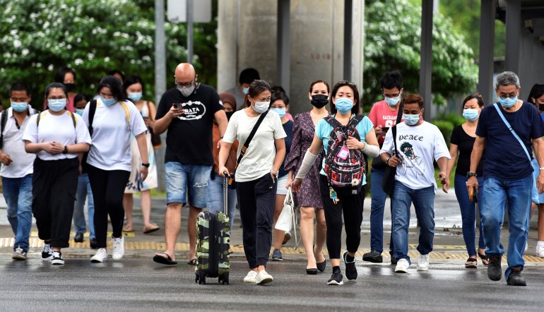 People wearing face masks cross a road amid the coronavirus disease (COVID-19) outbreak in Singapore May 14, 2021. REUTERS/Caroline Chia
