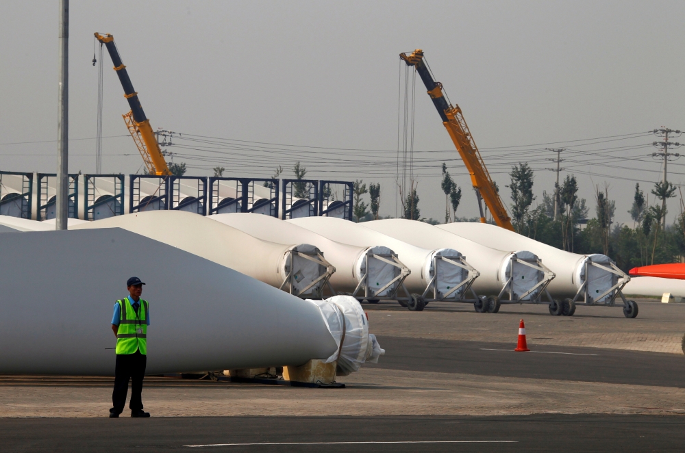 A security guard stands next to blades and bases for wind turbines on the grounds of the Vestas Wind Technology company's factory, located in the northern Chinese city of Tianjin September 14, 2010. Reuters/David Gray/File Photo