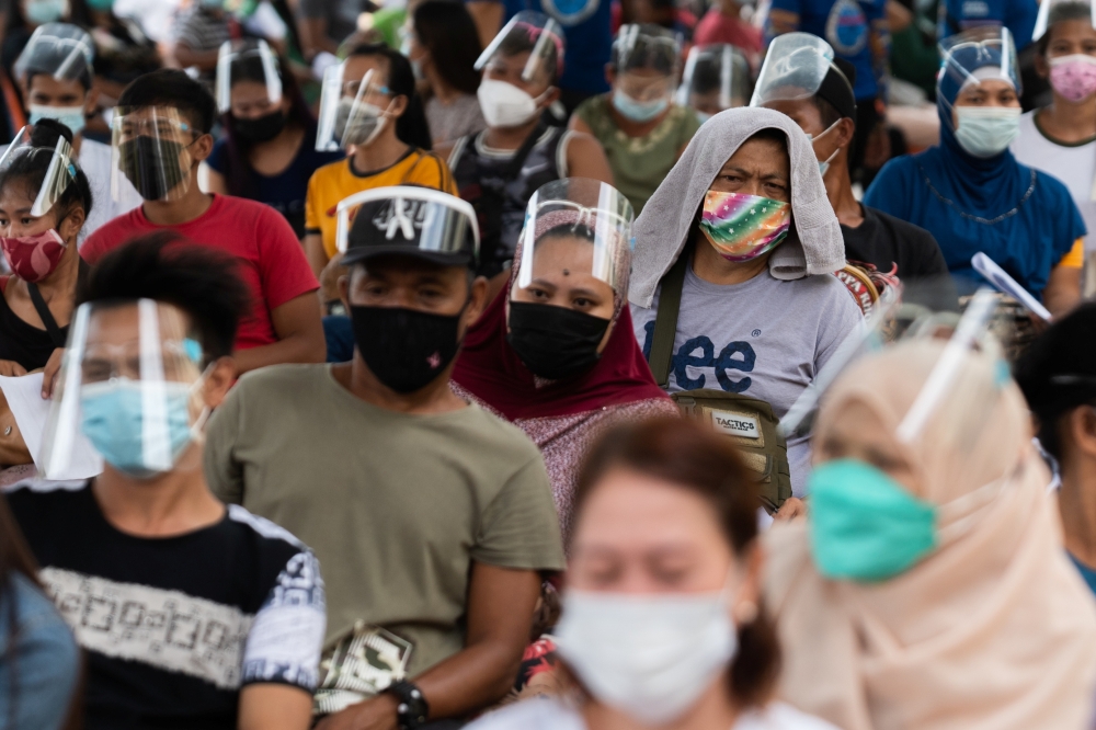 Residents queue to receive cash assistance from the government following the imposition of two-week lockdown to prevent the spread of the coronavirus Delta variant, at an elementary school in Manila, Philippines, August 11, 2021. REUTERS/Lisa Marie David