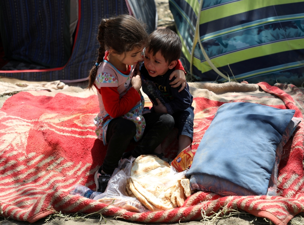 An internally displaced boy from northern provinces, who fled from his home due to the fighting between Taliban and Afghan security forces, is comforted by his sister in a public park that they use as shelter in Kabul, Afghanistan, August 10, 2021. Reuter