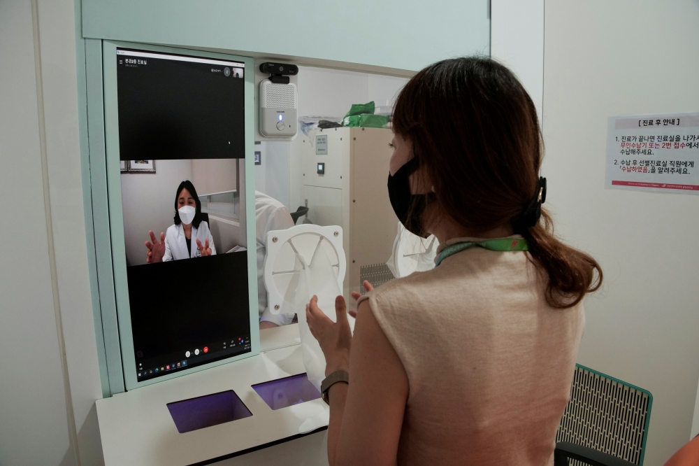 A hospital staff and Hallym University Medical Center (HUMC) director Lee Me-yeon (on screen) simulate a contactless medical check-up at a smart booth, amid the coronavirus disease (COVID-19) pandemic, in Anyang, South Korea August 12, 2021. REUTERS/Daewo