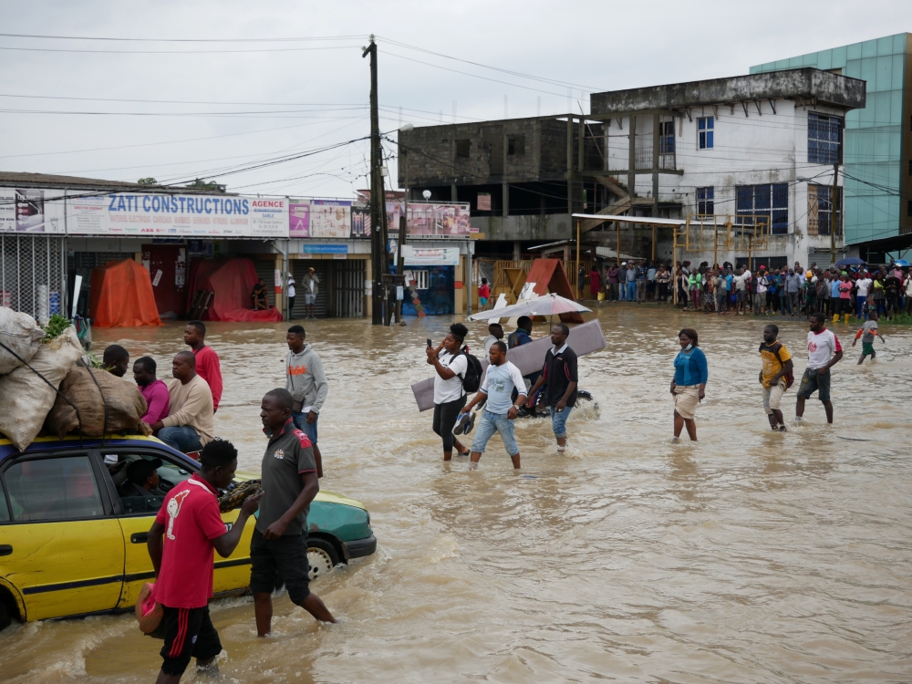 People make their way through a flooded street after the heavy rains in Douala, Cameroon, August 12, 2021. REUTERS/Joel Kouam