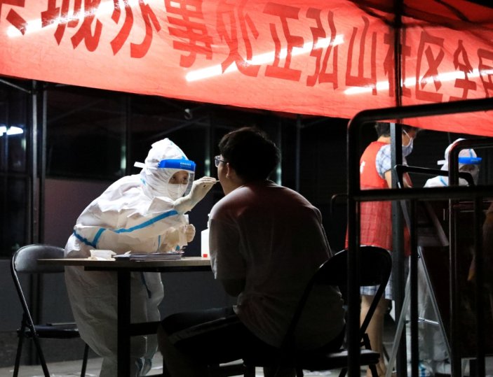 A medical worker in protective suit collects a swab from a resident for nucleic acid testing following new cases of the coronavirus disease (COVID-19) in Zhengzhou, Henan province, China early August 2, 2021. cnsphoto via Reuters