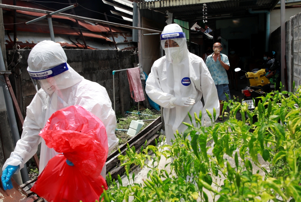 Buddhist monks wear personal protective equipment (PPE) as they perform coronavirus disease (COVID-19) testing in a community near their temple in Bangkok, Thailand August 4, 2021. Picture taken August 4, 2021. REUTERS/Soe Zeya Tun
