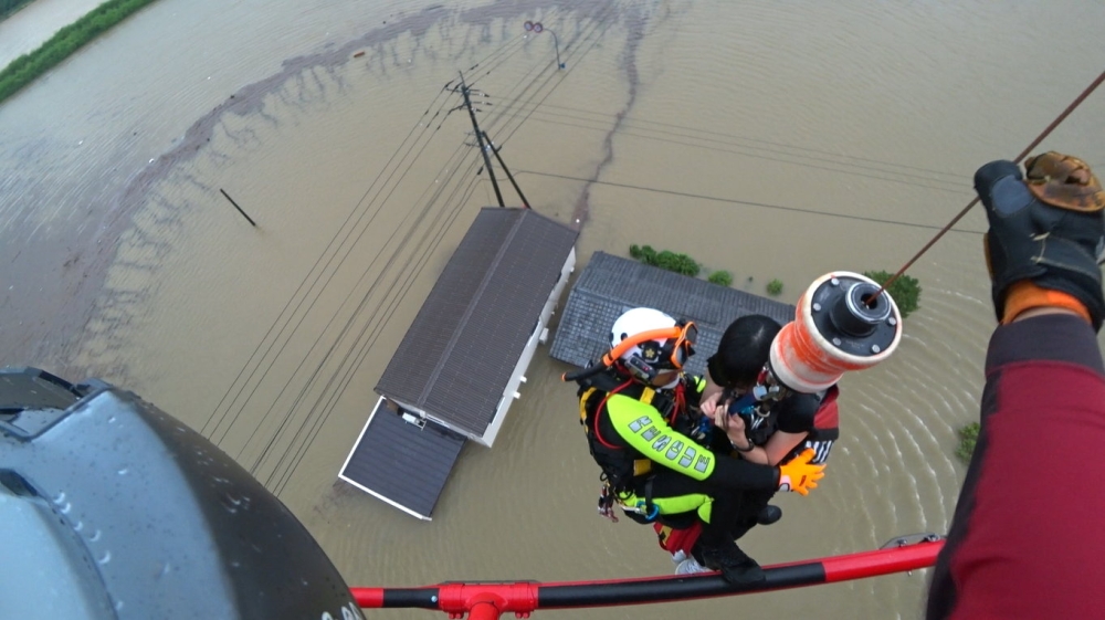 A Saga prefectural rescue worker lifting up a resident to a helicopter from submerged house caused by heavy rain during a rescue operation in Takeo, Saga Prefecture, southwestern Japan, in this handout image taken on August 14, 2021, and released by Saga 