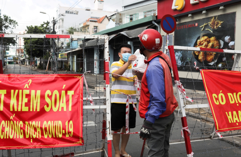 A man living in an area under lockdown receives food through a barricade during the coronavirus disease (COVID-19) pandemic in Ho Chi Minh City, Vietnam July 20, 2021. REUTERS/Stringer/File Photo