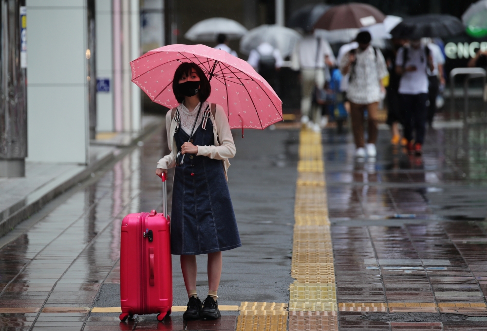 A woman wearing a protective mask, amid the coronavirus disease (COVID-19) outbreak, stands in the rain in Fukuoka, Fukuoka Prefecture, Japan, August 17, 2021. REUTERS/Kim Kyung-Hoon