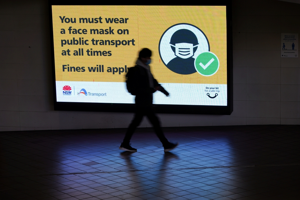 A person walks past a public health warning for passengers to wear face masks at a city centre transit station during a lockdown to curb the spread of an outbreak of the coronavirus disease (COVID-19) in Sydney, Australia, August 17, 2021. REUTERS/Loren E