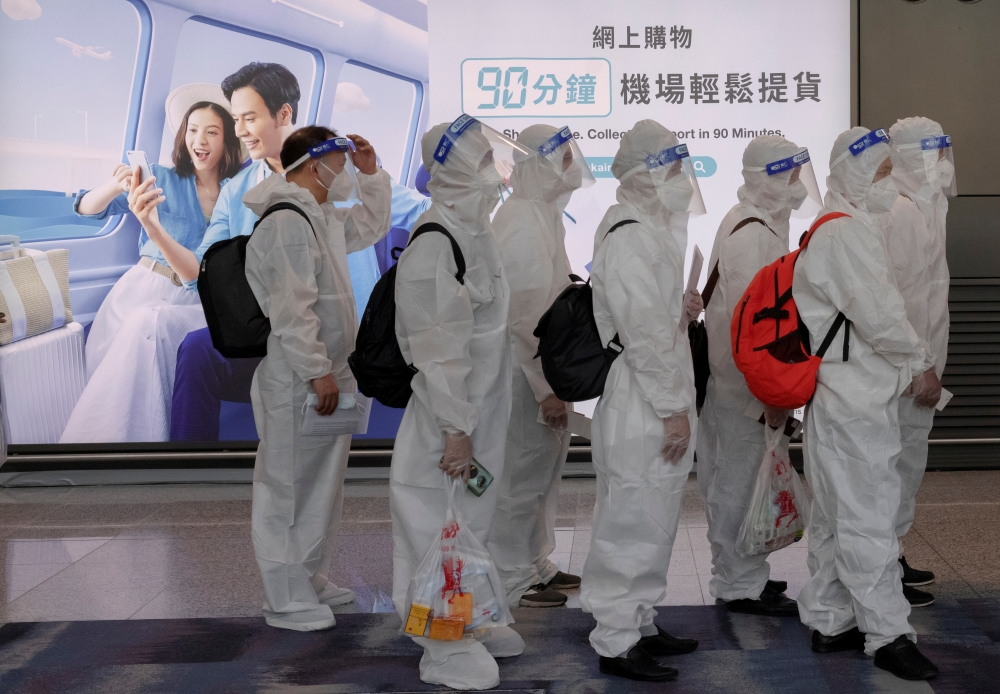 Passengers wearing protective suits (PPE) line up to board their plane for an international flight at Hong Kong airport amid the spread of the coronavirus disease (Covid-19), China July 9, 2021. Reuters/Thomas Peter//File Photo
