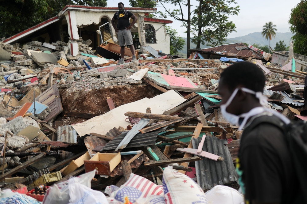 People stand near destroyed houses, after the earthquake that took place on August 14th, in Marceline, near Les Cayes, Haiti August 20, 2021. REUTERS/Henry Romero