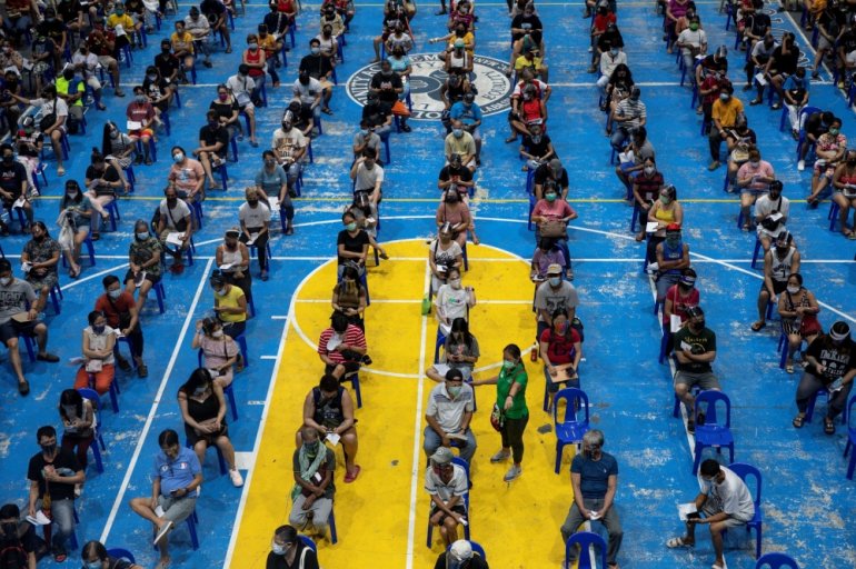 A government worker assists people queueing to get Moderna COVID-19 vaccine in school turned vaccination site that operates 24/7, in Manila, Philippines, August 9, 2021. REUTERS/Eloisa Lopez/File Photo
