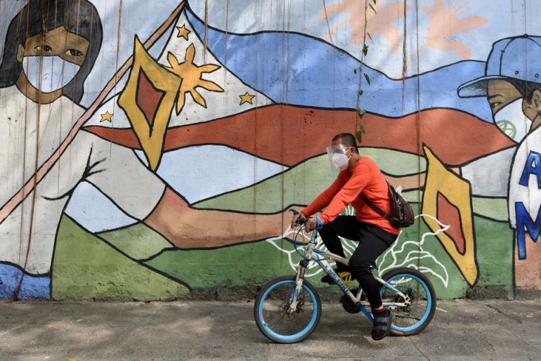 A man wearing a face mask and a face shield as protection against the coronavirus disease (COVID-19) passes by a mural dedicated to frontline workers, in Manila, Philippines, January 11, 2021. REUTERS/Lisa Marie David