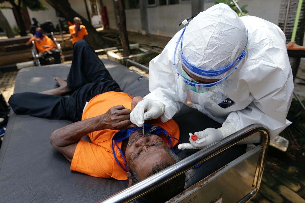 A man with mental illness reacts as a healthcare worker takes a swab sample to test for the coronavirus disease (COVID-19) at a social home in Jakarta, Indonesia, August 23, 2021. REUTERS/Ajeng Dinar Ulfiana