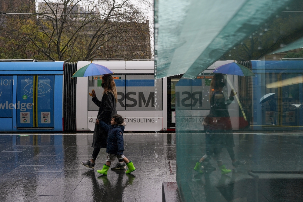 A masked woman with an umbrella walks with a child through the quiet city centre during a lockdown to curb the spread of a coronavirus disease (COVID-19) outbreak in Sydney, Australia, August 24, 2021. REUTERS/Loren Elliott