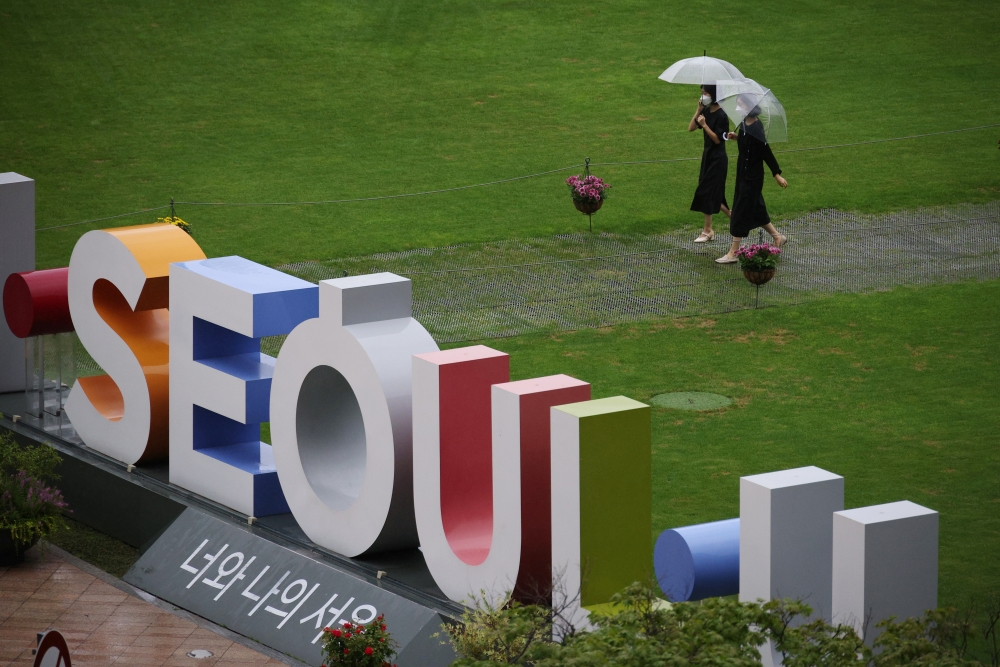 Women wearing masks to avoid contracting the coronavirus (COVID-19) disease walk at a park in Seoul, South Korea, August 24, 2021. REUTERS/Kim Hong-Ji