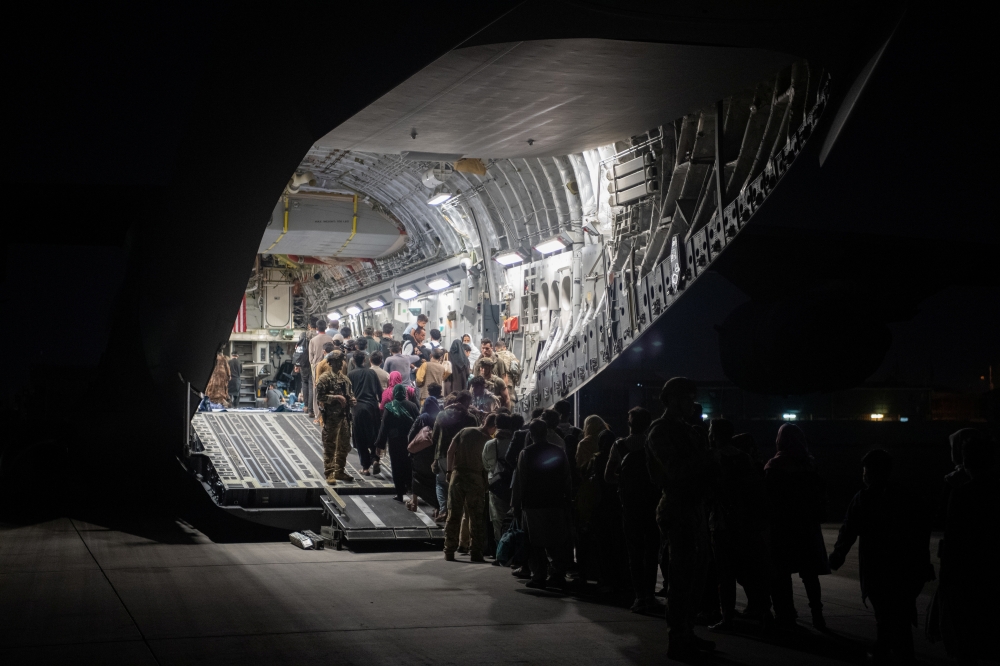 Afghans board a U.S. Air Force C-17 Globemaster III transport plane during an evacuation at Hamid Karzai International Airport, Afghanistan, August 22, 2021. Picture taken August 22, 2021. 