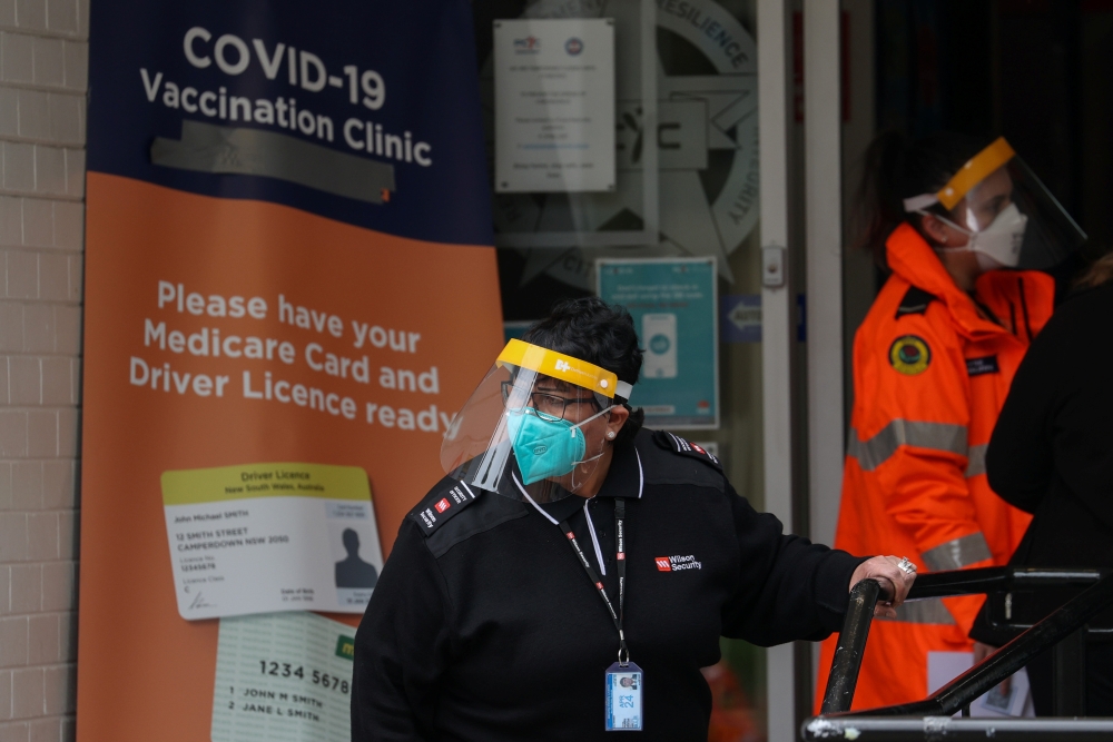 A staff member works at the front entrance of a coronavirus disease (COVID-19) vaccination clinic in the Bankstown suburb during a lockdown to curb an outbreak of cases in Sydney, Australia, August 25, 2021. REUTERS/Loren Elliott