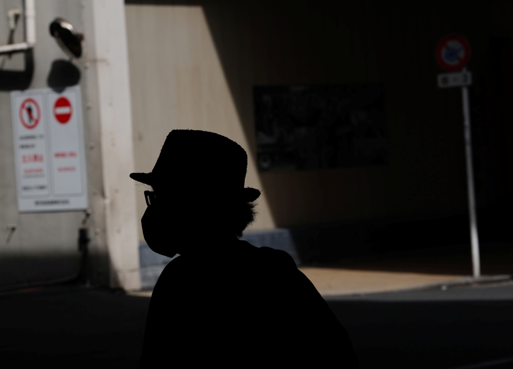 A man wearing a protective mask, amid the coronavirus disease (COVID-19) pandemic, is silhouetted in Tokyo, Japan, August 25, 2021. REUTERS/Kim Kyung-Hoon