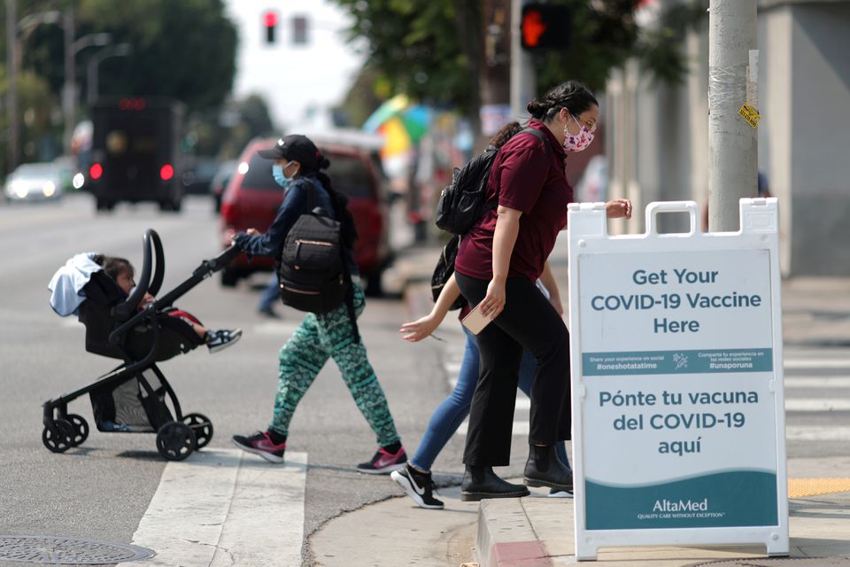 People walk past a sign for a coronavirus disease (COVID-19) vaccination clinic in Los Angeles, California, U.S., August 17, 2021. REUTERS/Lucy Nicholson

