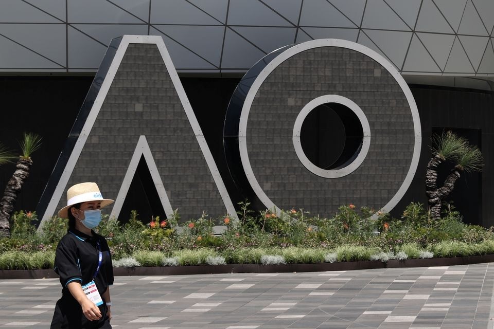 A person wearing a protective face mask walks past an Australian Open logo at Melbourne Park in advance of the tennis tournament, which will start later than usual due to a coronavirus disease (COVID-19) postponement, in Melbourne, Australia, January 31, 