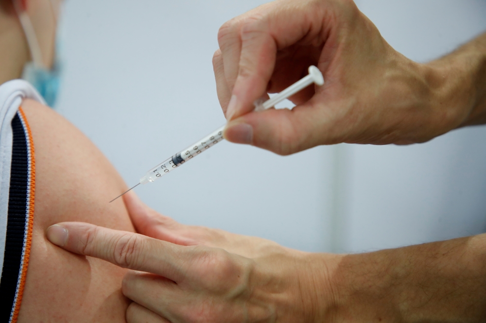 A medical worker administers a dose of the Pfizer-BioNTech 