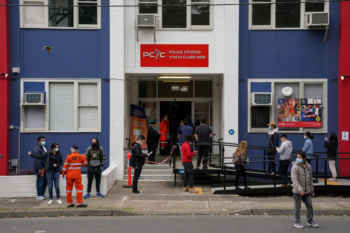 FILE PHOTO: People wait in line outside a coronavirus disease (COVID-19) vaccination clinic in the Bankstown suburb during a lockdown to curb an outbreak of cases in Sydney, Australia, August 25, 2021. REUTERS/Loren Elliott/File Photo

