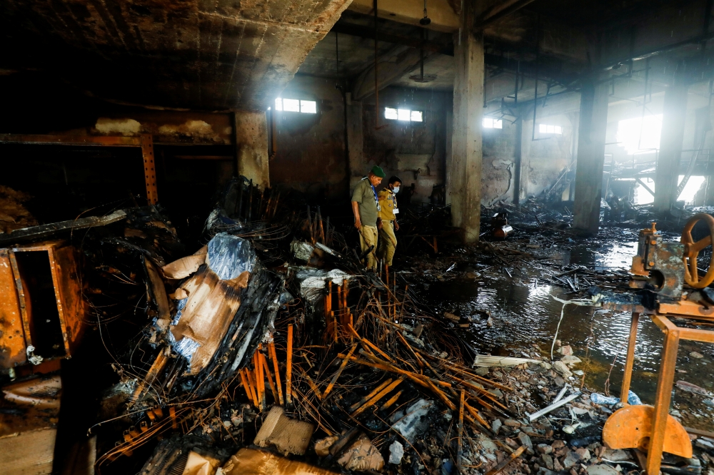 Members of the scout emergency response team, survey amid the burned wreckage, after a fire broke out at a multi-story chemical factory, in Karachi, Pakistan, August 27, 2021. REUTERS/Akhtar Soomro