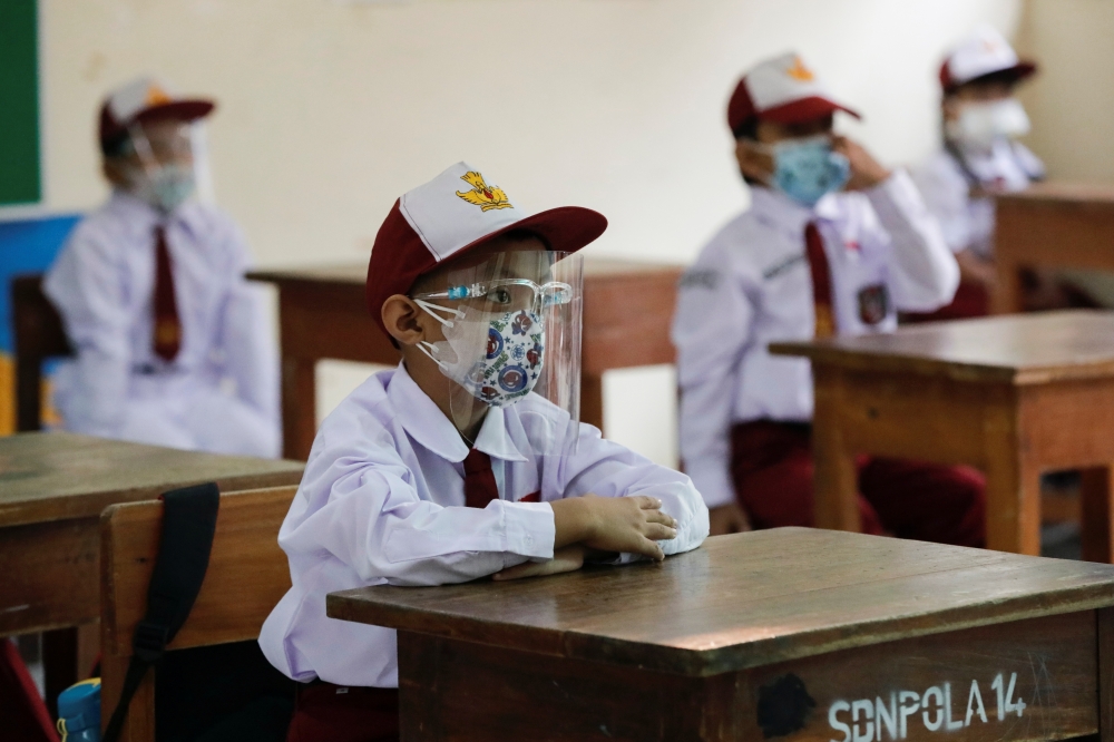 Elementary school students wearing face masks and face shields attend class, as schools reopen on trial basis after the government extended restrictions to curb the spread of coronavirus disease (COVID-19) in Jakarta, Indonesia, August 30, 2021. REUTERS/A