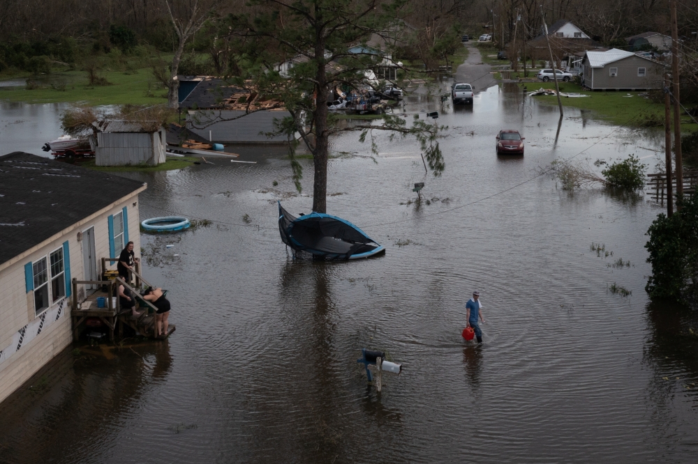A man walks back to his home after sharing fuel with his neighbors, to use for their generator, in the aftermath of Hurricane Ida in Cut Off, Louisiana, U.S., August 30, 2021. Picture taken with a drone. REUTERS/Adrees Latif