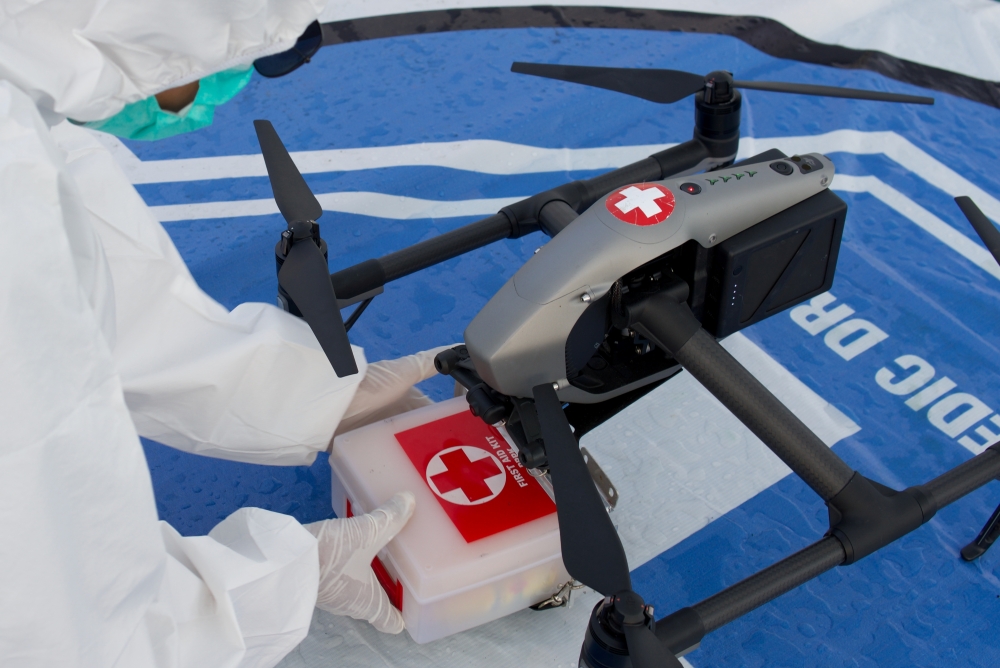 A medical worker wearing personal protective equipment (PPE) takes a box of medical supplies that is being delivered with a drone on the deck of a passenger ship owned by the state-owned shipping company PT PELNI, KM Umsini, which has been modified as an 
