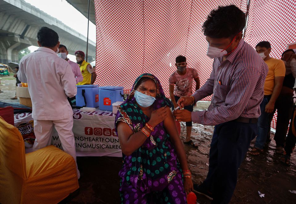 A woman receives a dose of COVAXIN coronavirus disease (COVID-19) vaccine manufactured by Bharat Biotech, during a vaccination drive organised by SEEDS, an NGO which normally specialise in providing relief after floods and other natural disasters, at an u