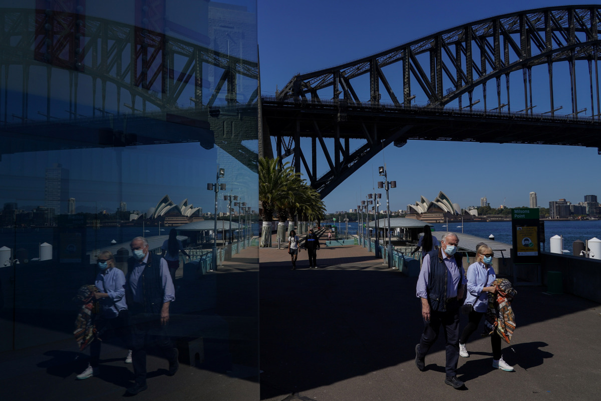 People in protective face masks walk past the Sydney Harbour Bridge during a lockdown to curb the spread of a coronavirus disease (COVID-19) outbreak in Sydney, Australia, September 3, 2021. REUTERS/Loren Elliott
