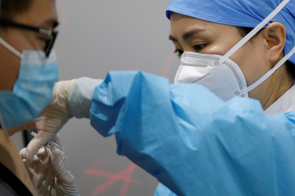 A medical worker prepares to administer a dose of a coronavirus disease (COVID-19) vaccine to a man at a vaccination site, during a government-organized visit, in Beijing, China January 15, 2021. REUTERS/Carlos Garcia Rawlins/File Photo
