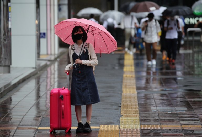 A woman wearing a protective mask, amid the coronavirus disease (COVID-19) outbreak, stands in the rain in Fukuoka, Fukuoka Prefecture, Japan, August 17, 2021. REUTERS/Kim Kyung-Hoon
