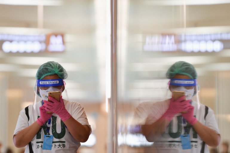 A person wearing a face shield and protective face masks uses her phone at the shopping mall on the first day of coronavirus restrictions lift on retail and dining in Bangkok and other high-risk areas to revive the economy, as the country battles its wors