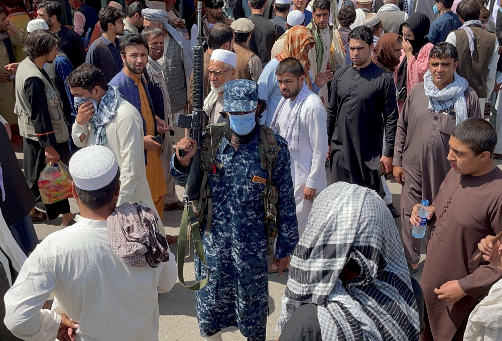 FILE PHOTO: A member of Taliban security forces stands guard among crowds of people walking past in a street in Kabul, Afghanistan September 4, 2021. REUTERS/Stringer/File Photo