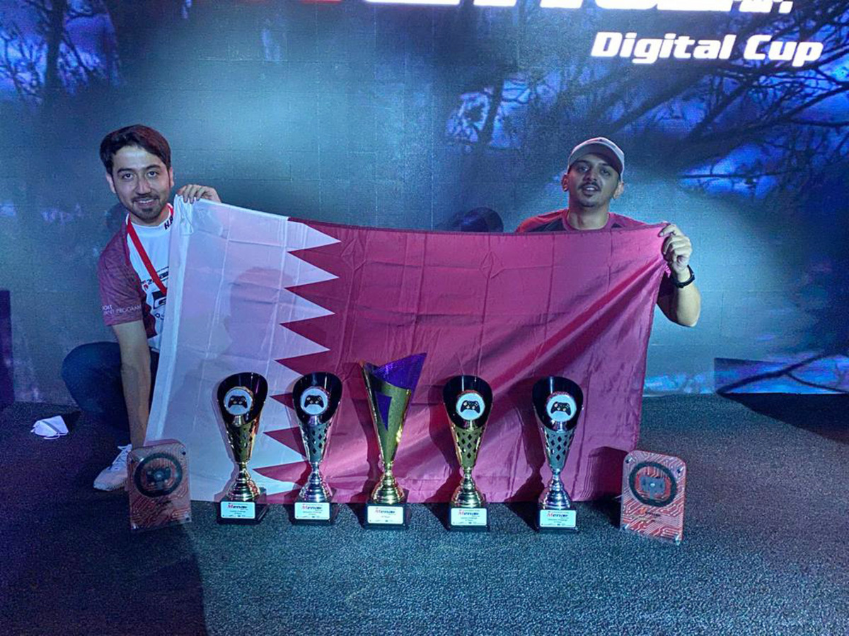 Khalid Al Maraghi and Faesal Al Yafei pose with the Qatari flag and their trophies.