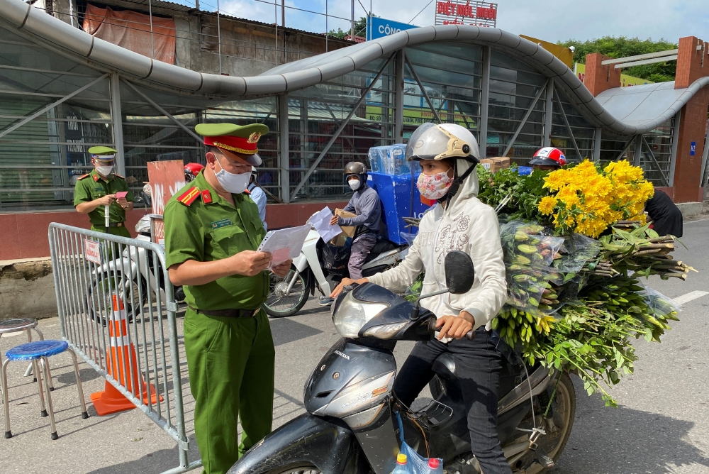 Vietnam police officers inspect authorised travel documents of commuters at a check point during the first day of the extended lockdown in Hanoi, Vietnam, September 6, 2021. REUTERS/Stringer/File Photo