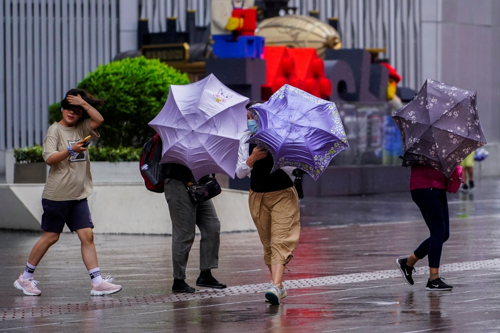 People walk on a street, as typhoon Chanthu approaches, in Shanghai, China September 13, 2021. REUTERS/Aly Song
