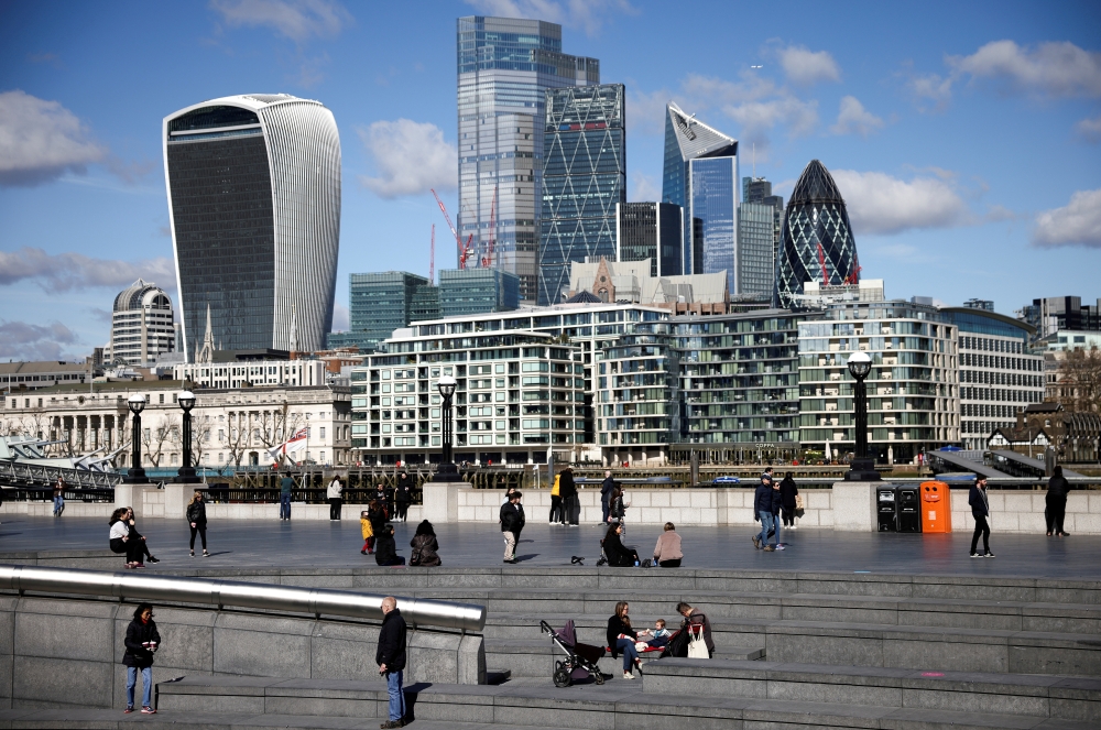 The City of London financial district can be seen as people walk along the south side of the River Thames, amid the coronavirus disease (COVID-19) outbreak in London, Britain, March 19, 2021. Reuters/Henry Nicholls